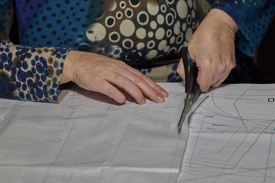Hands cutting a paper sewing pattern with scissors