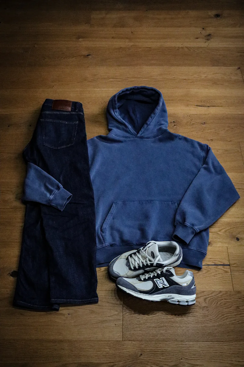 Navy hoodie and jeans laid flat